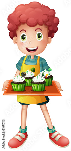 A boy holding a tray of cupcakes