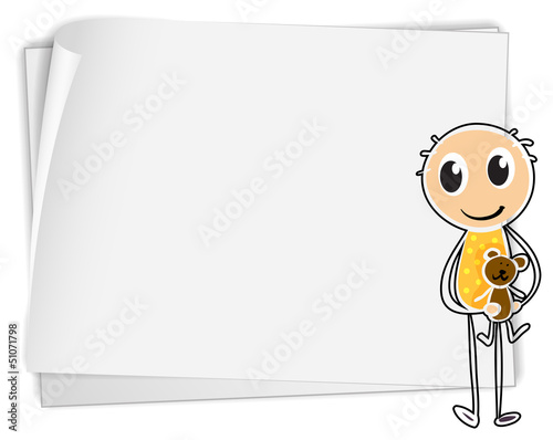 A boy holding a teddy bear beside a white paper