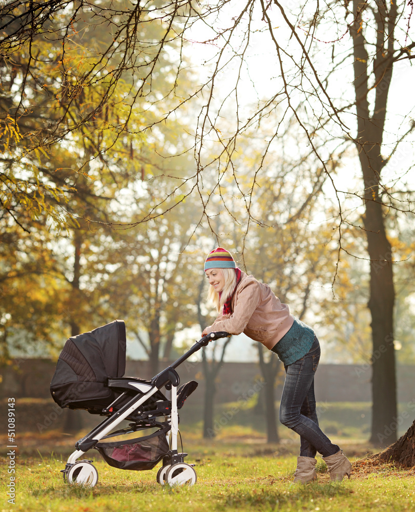 Young mother with a baby carriage walking in a park