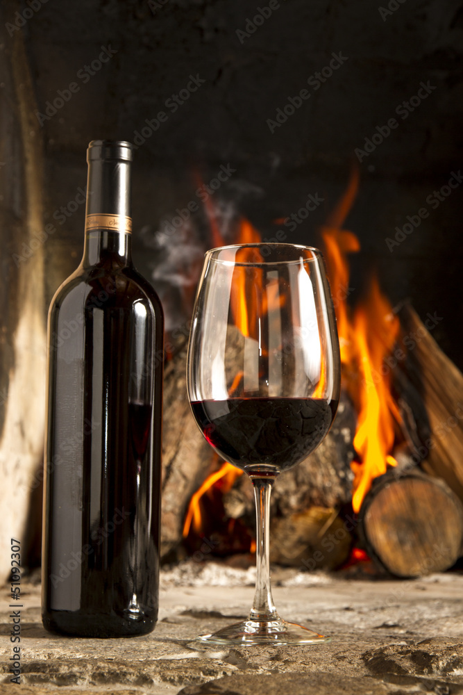 Copa de vino tino con fuego de chimenea de fondo.