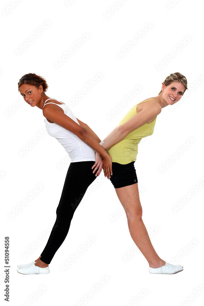 Two women in gym clothing forming the letter X Two women in gym clothing forming the letter X