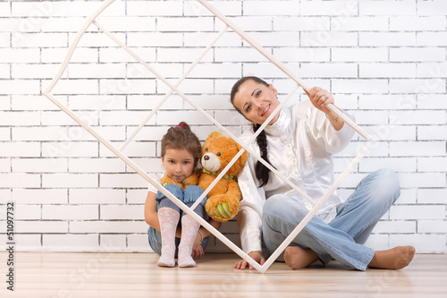 Mother and 5 year old daughter sitting by the wall