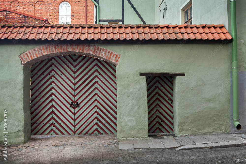 Green wall with wooden gate and door.Tallinn, Estonia