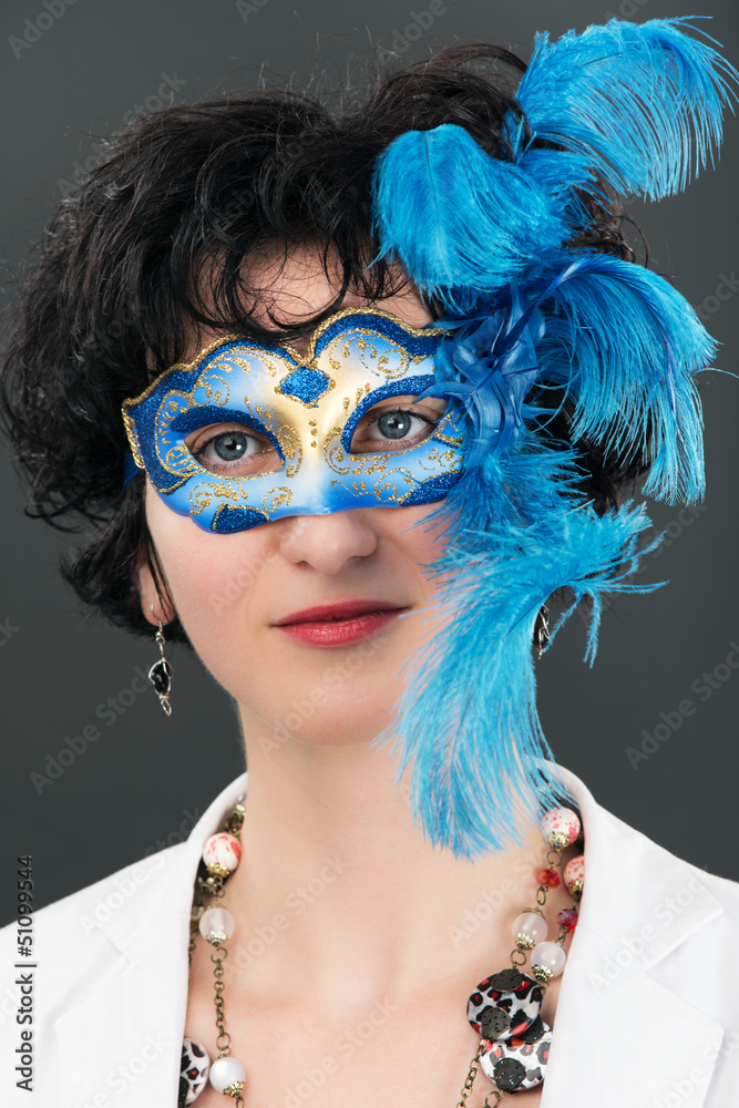 Woman with blue eyes wearing a feathered Venetian mask