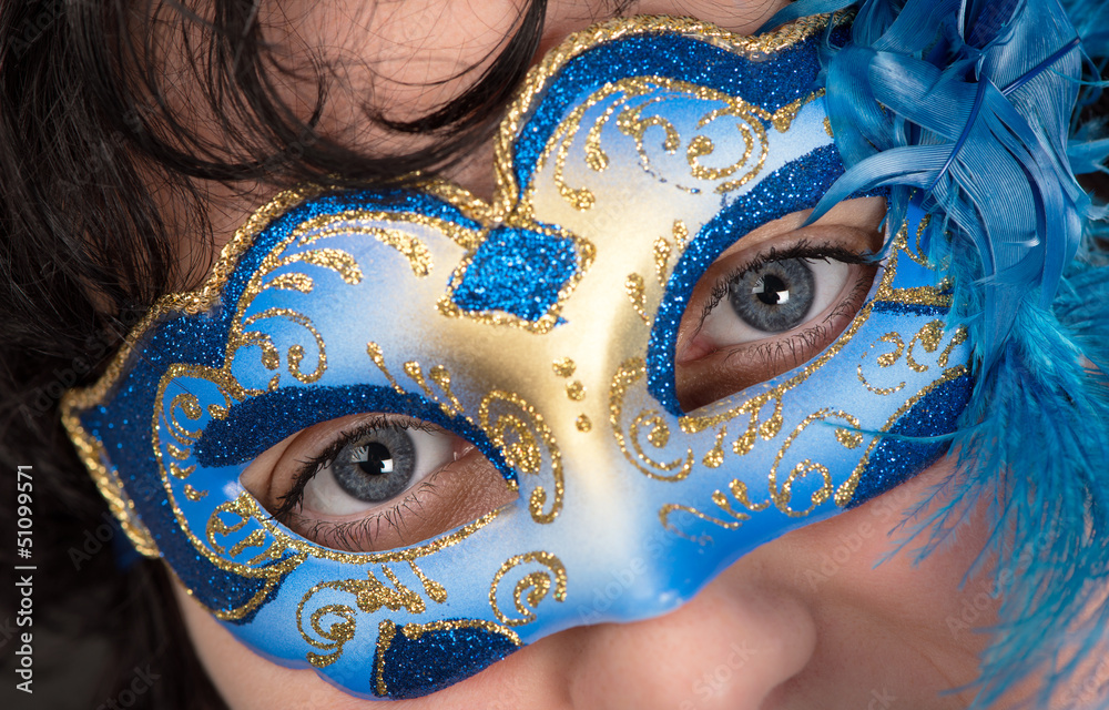 Woman with blue eyes wearing a feathered Venetian mask