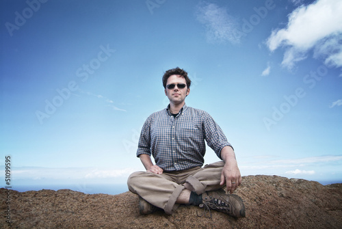 Man is sitting on a rock on top of the world, cotemplating
