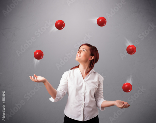young girl standing and juggling with red balls photo