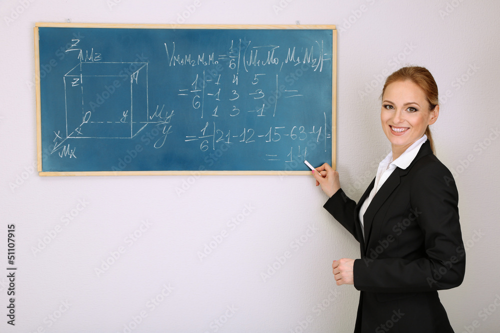 Portrait of teacher woman writing on the chalkboard in Portrait of teacher woman writing on the chalkboard in