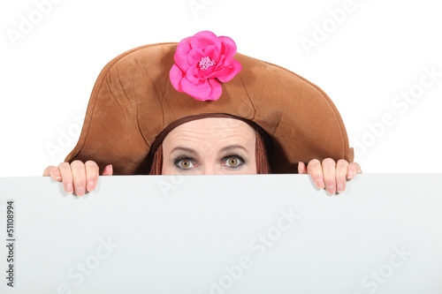 Woman hiding wearing a big brown hat