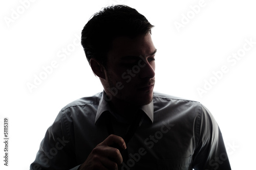 Businessman silhouette loosen a bit the tie after work