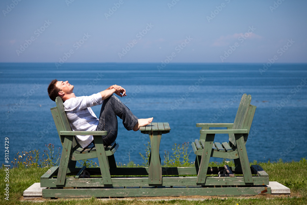 Fototapeta premium Young man sitting on the bench