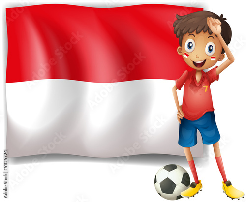 A boy with a soccer ball standing in front of the Monaco Flag
