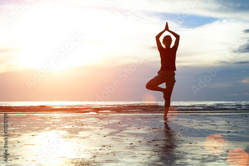 Silhouette woman practicing yoga on the beach. © De Visu