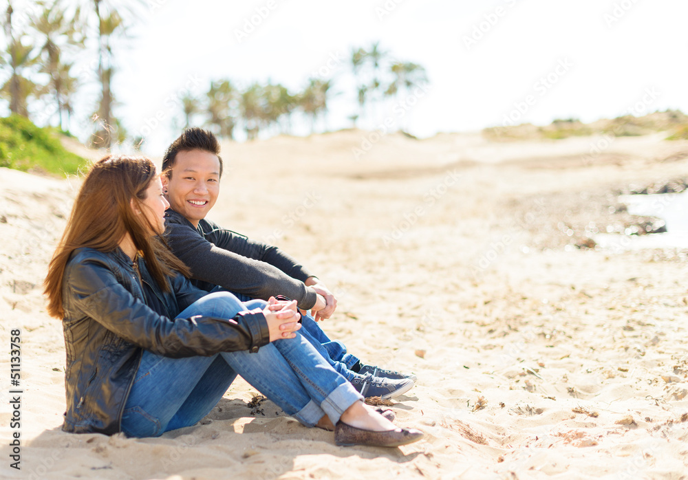 Fototapeta premium Young Couple Sitting On Beach