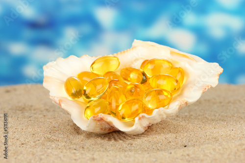 fish oil in the shell in the sand on a blue background