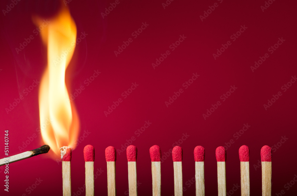 Burning match setting fire to its neighbors - obrazy, fototapety, plakaty 