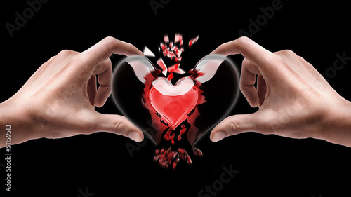 Man's hands holding broken heart isolated on black background