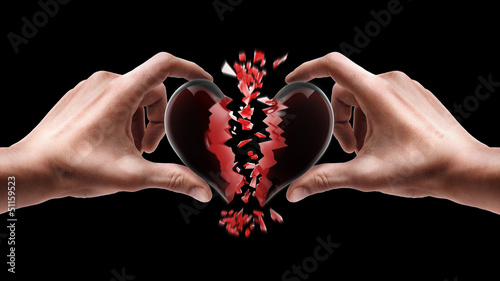 Man's hands holding broken heart isolated on black background