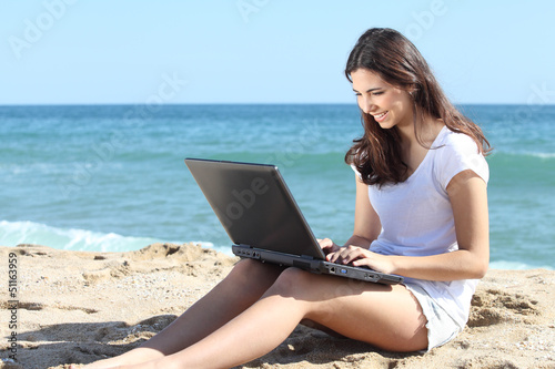 Beautiful woman with a laptop on the beach
