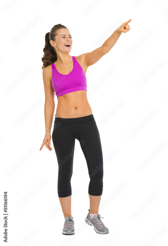 Portrait of smiling fitness young woman pointing on copy space Portrait of smiling fitness young woman pointing on copy space
