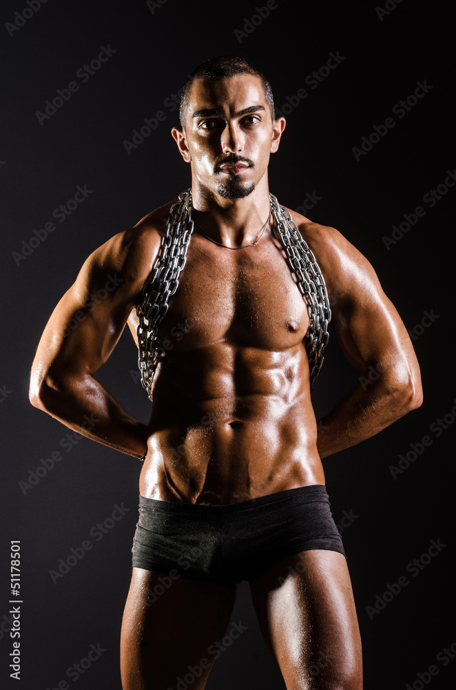 Muscular man with chain on black background