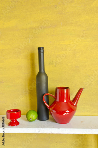 still-life with black bottle, red teapot and lemon