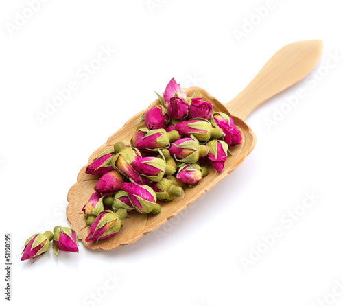 tea rose flowers in a wooden spoon isolated on white