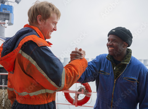Fotografia European deck officer friendly shakes a hand of African motorman