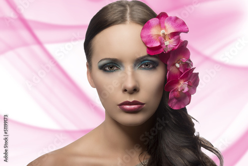 pretty brunette with flowers near face . FLOWERS ARE FAKE