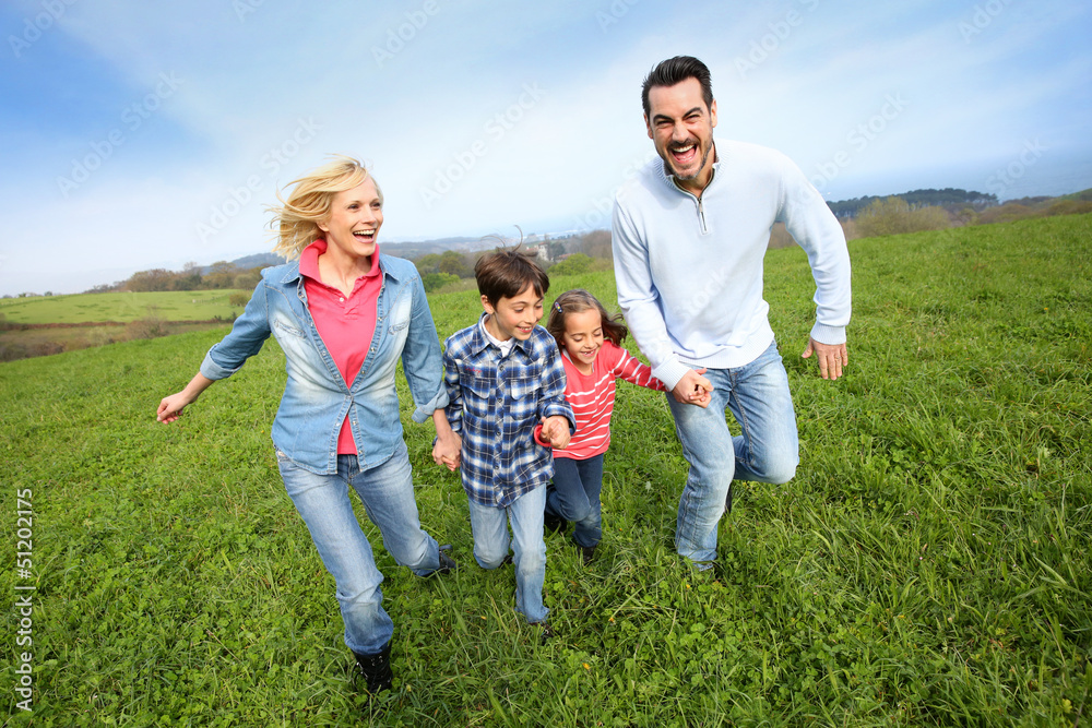 Family of four running together in natural landscape Family of four running together in natural landscape