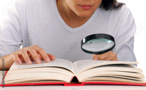 Mujer leyendo un libro sujetando una lupa. photo