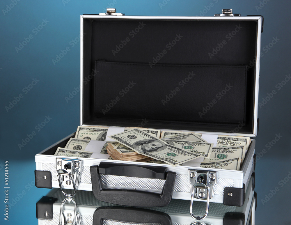 Suitcase with 100 dollar bills on blue background Suitcase with 100 dollar bills on blue background