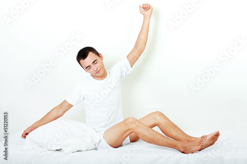 happy young man stretching on the bed