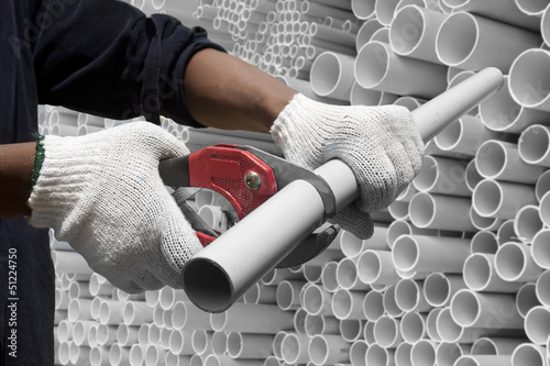 Worker cutting pvc pipe in construction site photo