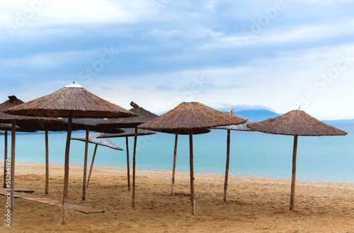 Fototapeta Naklejka Na Ścianę i Meble -  Straw Umbrella on beach with morning blue sky summer holiday