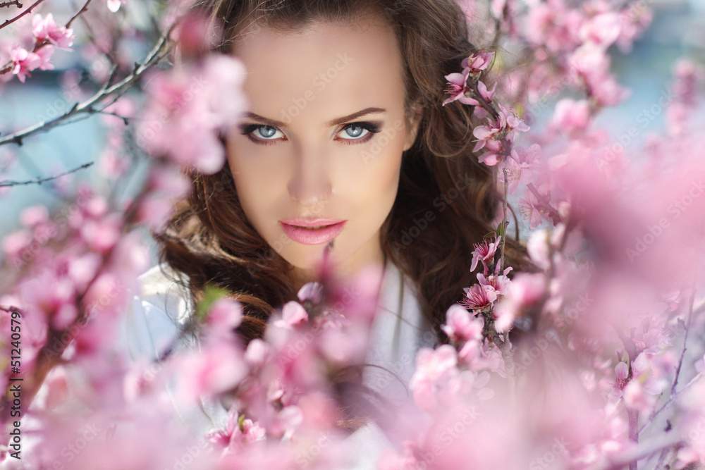 Stare.  Beautiful woman in pink blossoms on spring day