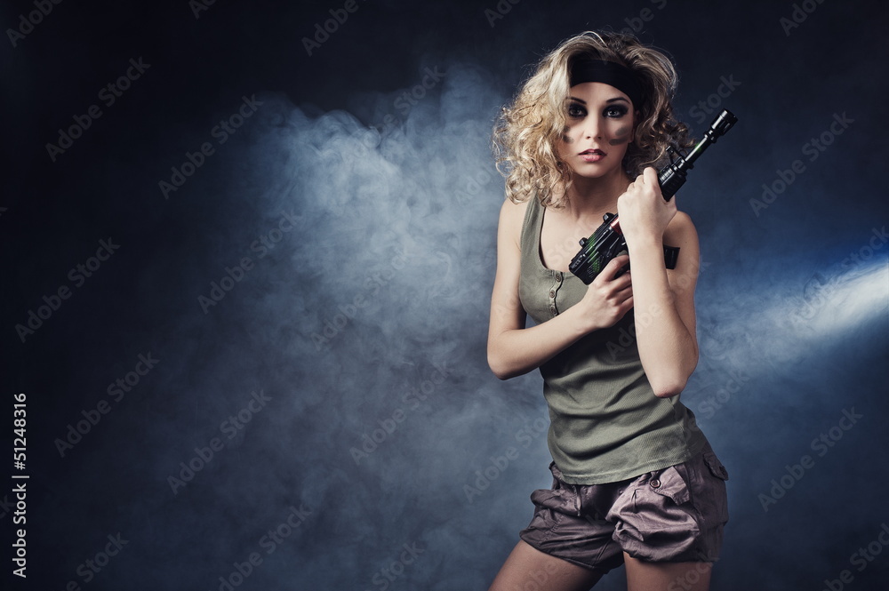 Fototapeta premium Military girl wearing a sexy outfit with a gun in his hand