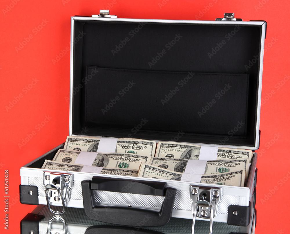 Suitcase with 100 dollar bills on red background Suitcase with 100 dollar bills on red background