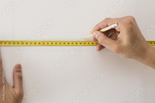 measuring tape and pencil marking with a white wall