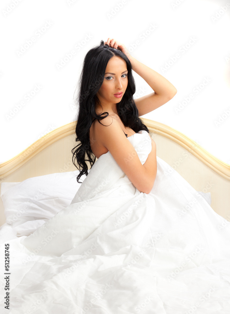 Girl in white lingerie sitting in bed on a white background.. Girl in white lingerie sitting in bed on a white background..