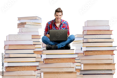 Young man sitting on a stack of books with a laptop