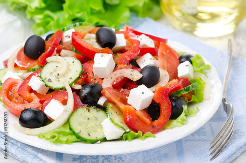 Greek salad with feta cheese, olives and vegetables on the plate