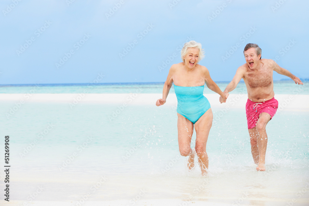 Senior Couple Having Fun In Sea On Beach Holiday