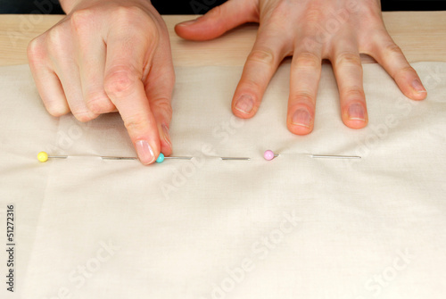 Closeup of large upholstery pins being pinned into plain fabric