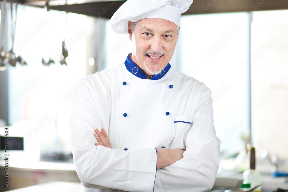 male chef smiling while standing in restaurant kitchen