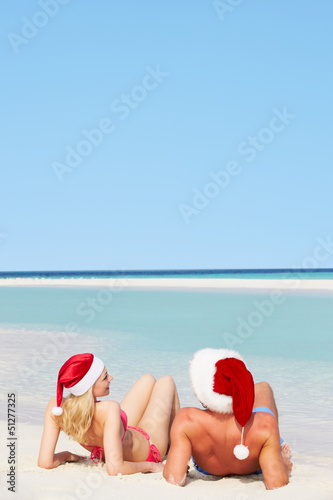 Couple Sitting On Beach Wearing Santa Hats