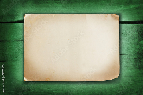 Paper sheet with shabby corners on a green painted wood