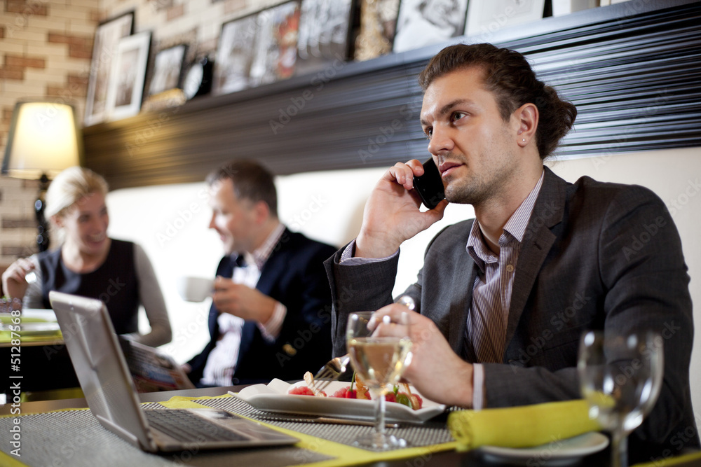 The businessman using the laptop and mobile in cafe.