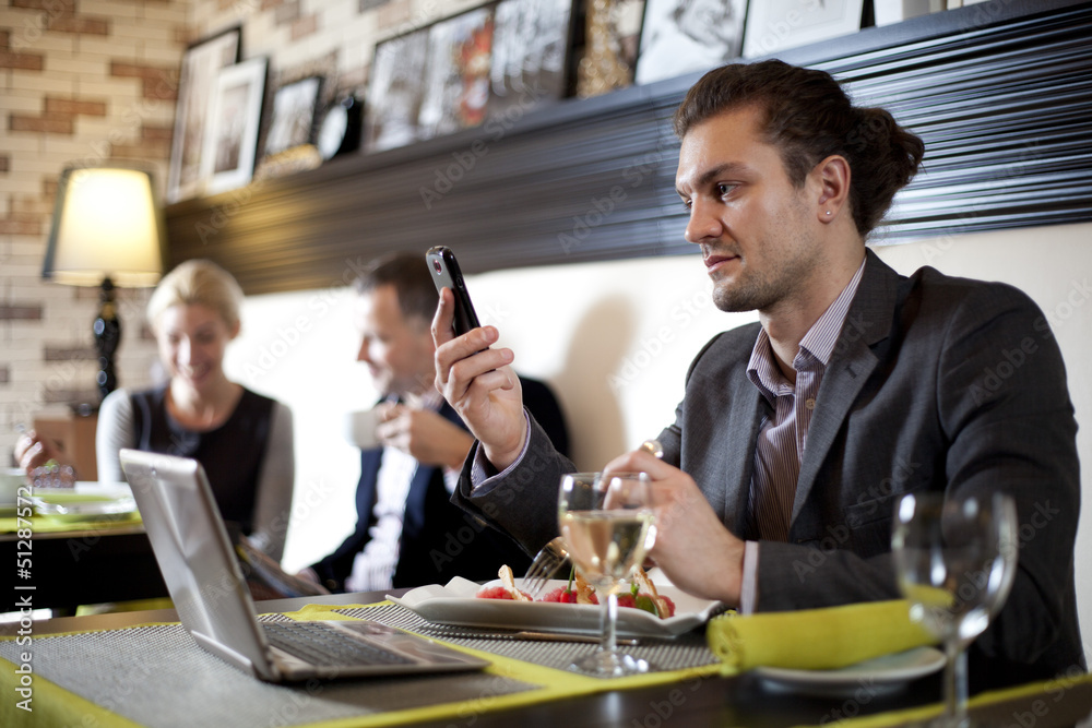 The businessman using the laptop and mobile in cafe.