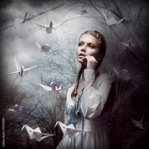 Inspiration. Woman with Flying Origami Swans in Mystic Forest photo